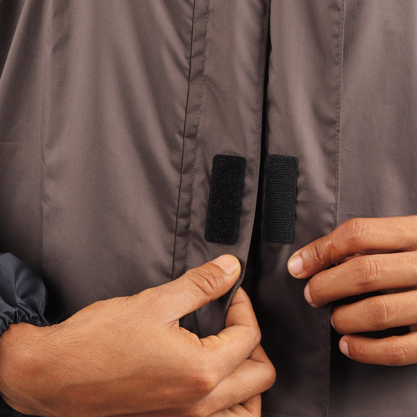 Velcro-secured storm flap on the grey and blue ARCUS rainwear jacket for added weather protection.