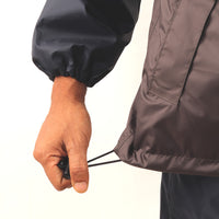 Drawstring adjuster on the side of the grey and blue ARCUS rainwear jacket for a secure and adjustable fit.